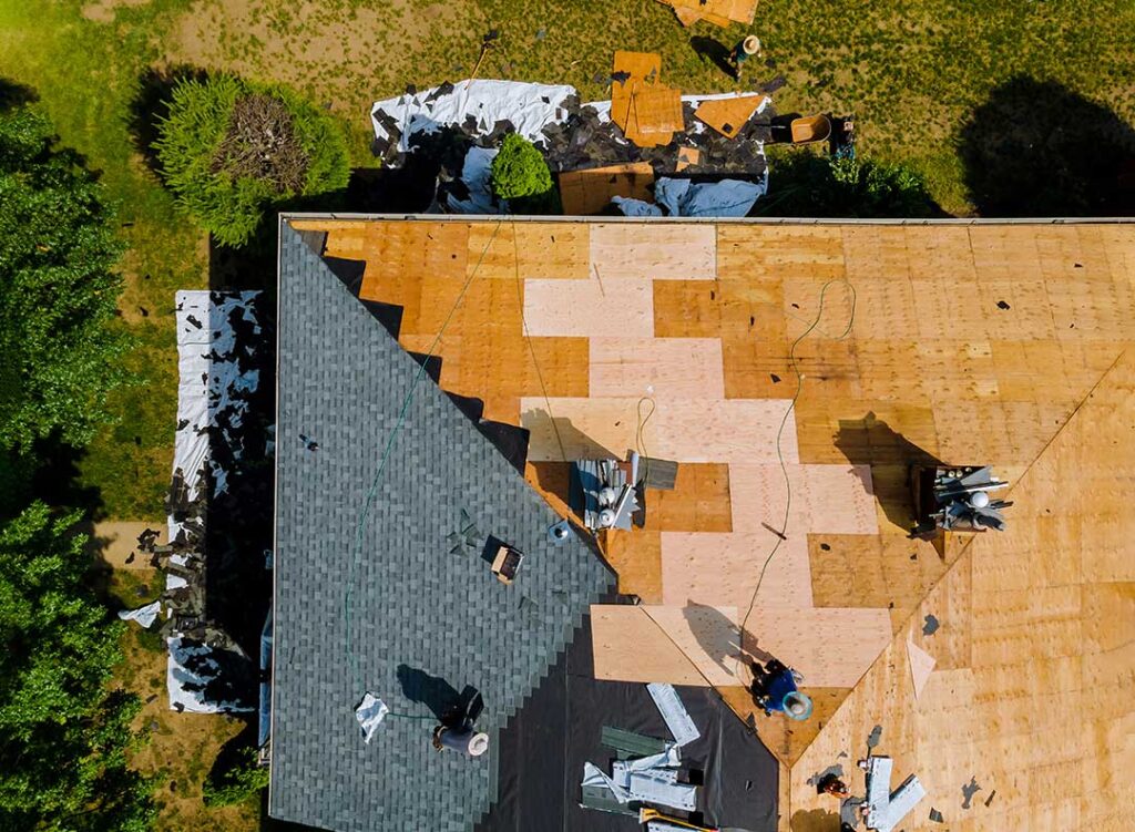 A well-maintained residential roof viewed from the street with clean shingles, gutters, and light snow cover